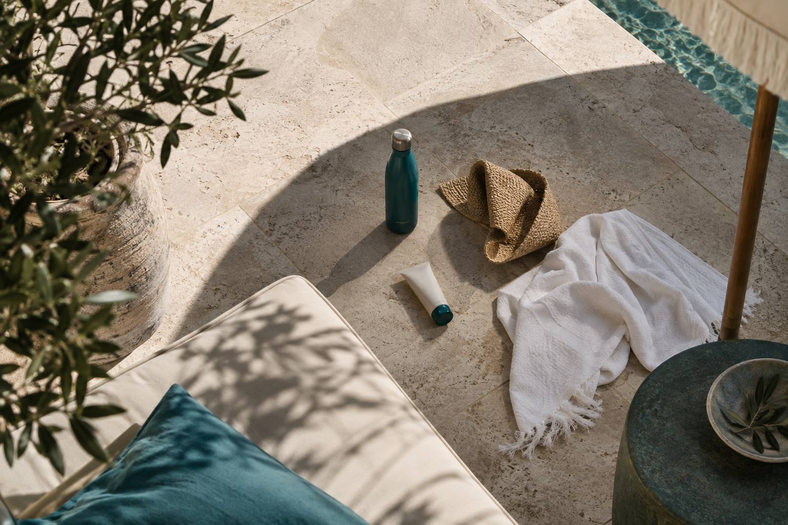 Gourde et casquette posees a l'ombre d'un parasol sur une terrasse